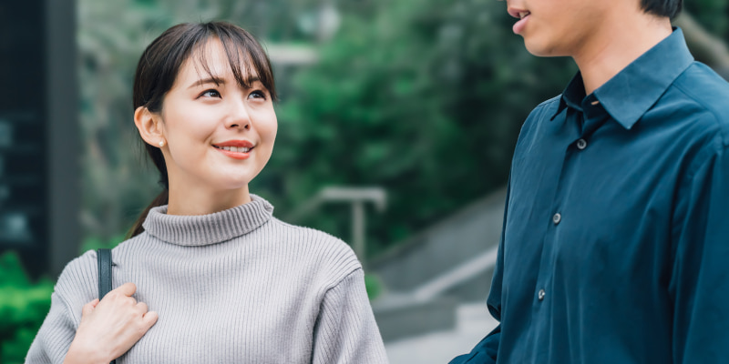 男性と目を合わせて笑顔で会話する女性の写真